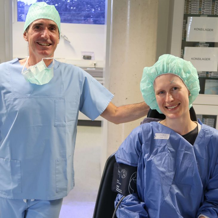 Augenarzt mit Patientin in OP-Kleidung